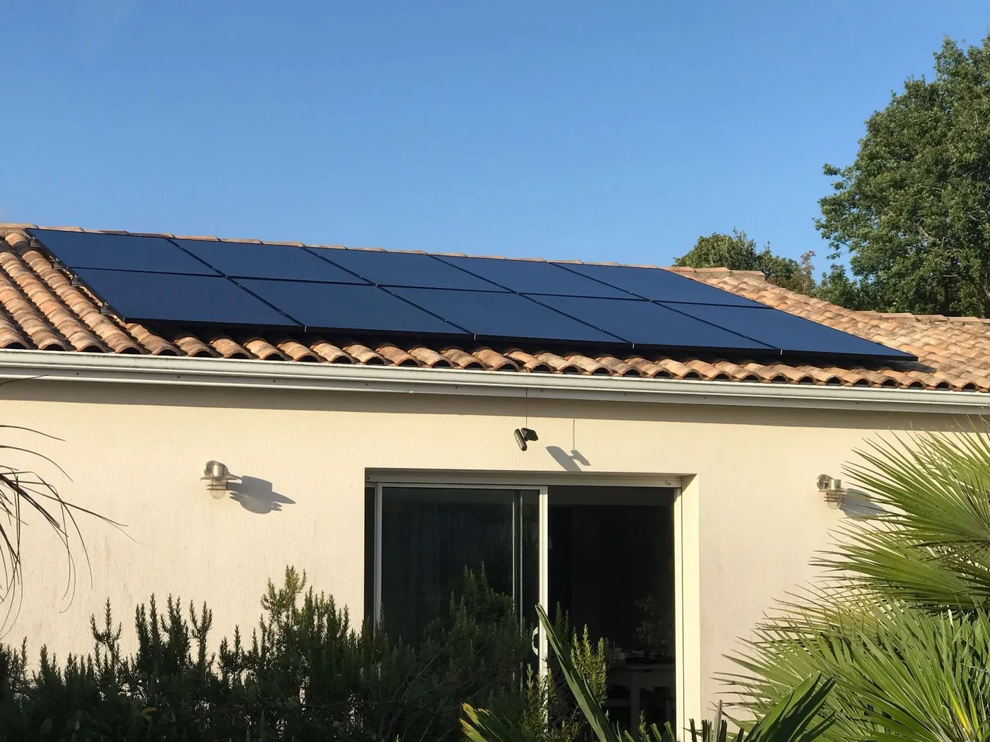 Villa équipée de panneaux solaires noirs sur toiture en tuiles, installée par Indépendance Énergétique